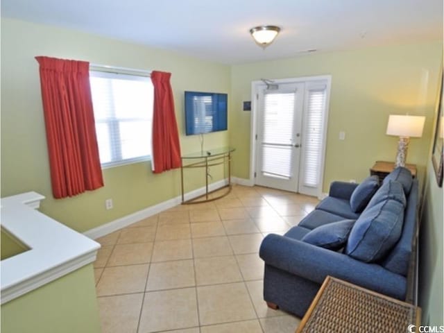 living room with french doors, baseboards, and light tile patterned floors