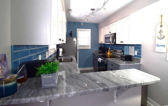 kitchen featuring sink, stainless steel appliances, kitchen peninsula, decorative backsplash, and white cabinets