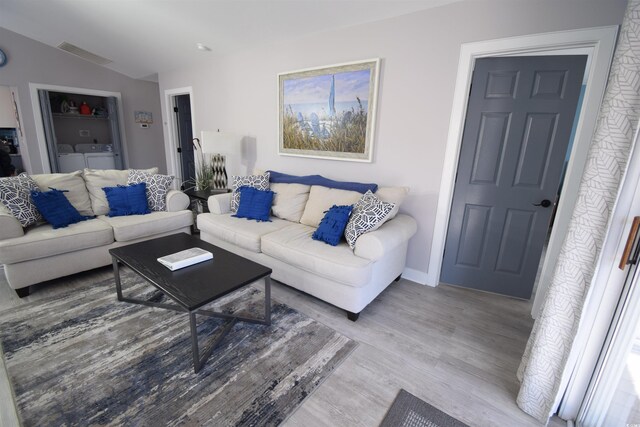 living room featuring hardwood / wood-style flooring, lofted ceiling, and separate washer and dryer