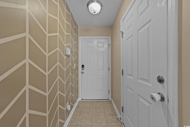 doorway to outside featuring a textured ceiling and light tile patterned flooring