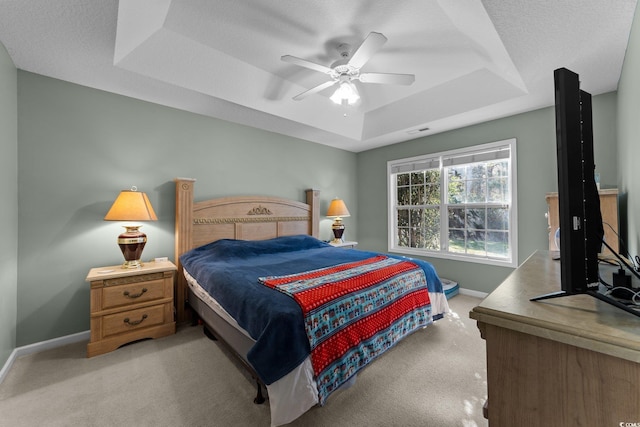 carpeted bedroom with a textured ceiling, a tray ceiling, and ceiling fan