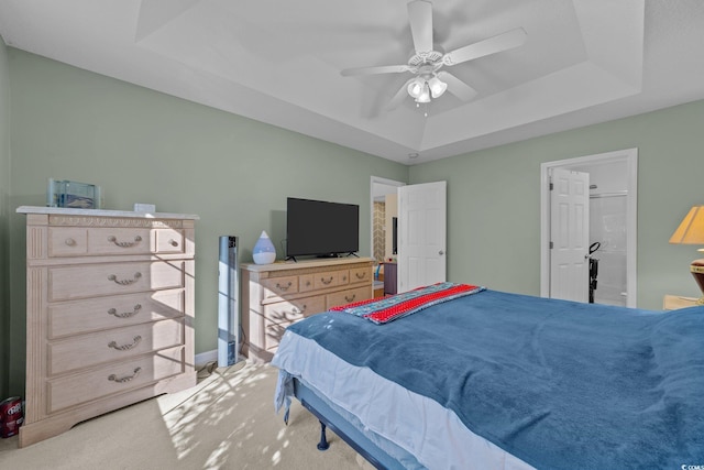 bedroom featuring ceiling fan, a raised ceiling, and light colored carpet