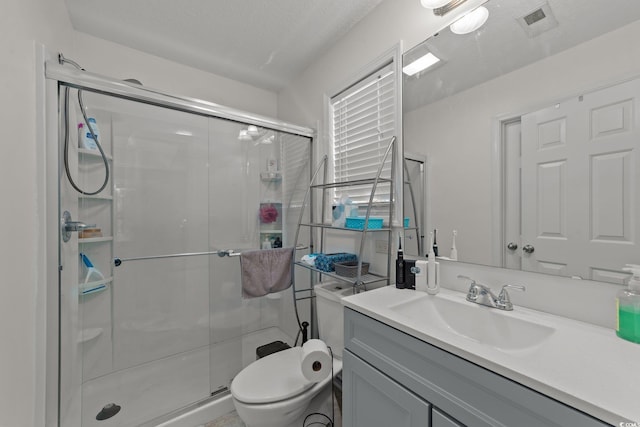 bathroom with vanity, a shower with shower door, a textured ceiling, and toilet