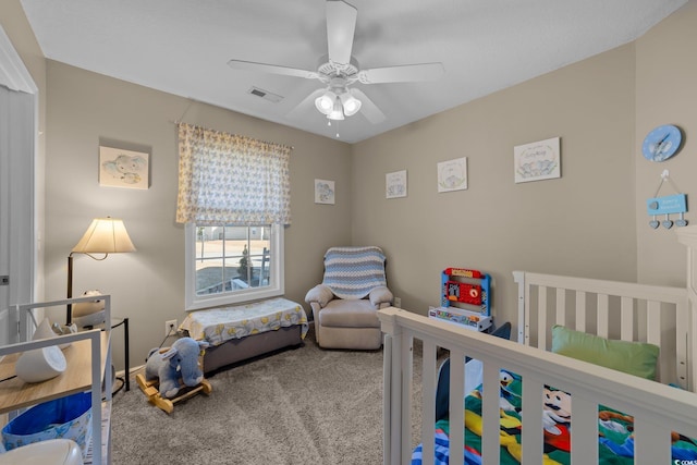 bedroom featuring a crib, carpet floors, and ceiling fan