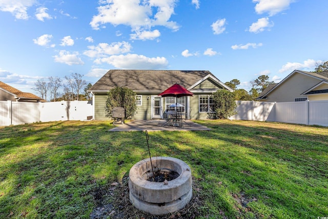 rear view of house with a patio, a fire pit, and a lawn