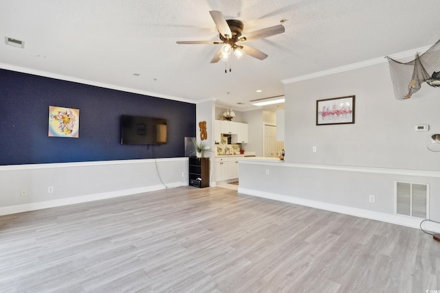 unfurnished living room featuring ceiling fan, light wood-type flooring, ornamental molding, and a textured ceiling