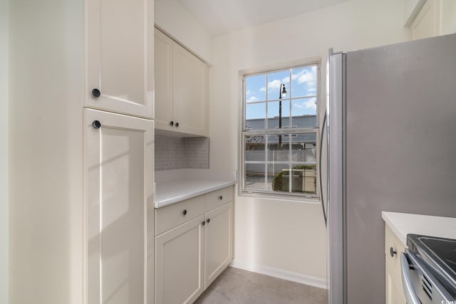 kitchen featuring backsplash, white cabinets, light tile patterned floors, and appliances with stainless steel finishes