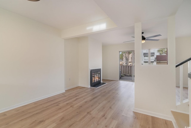 unfurnished living room featuring a multi sided fireplace, light hardwood / wood-style flooring, and ceiling fan