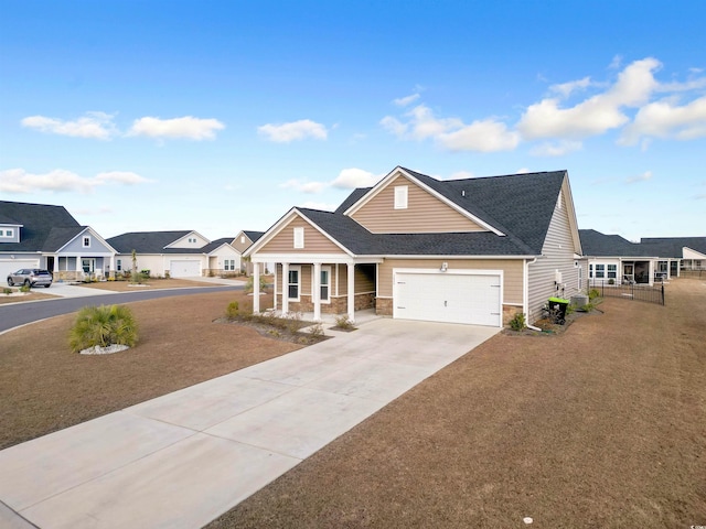 view of front of property with a porch, concrete driveway, a garage, stone siding, and a residential view