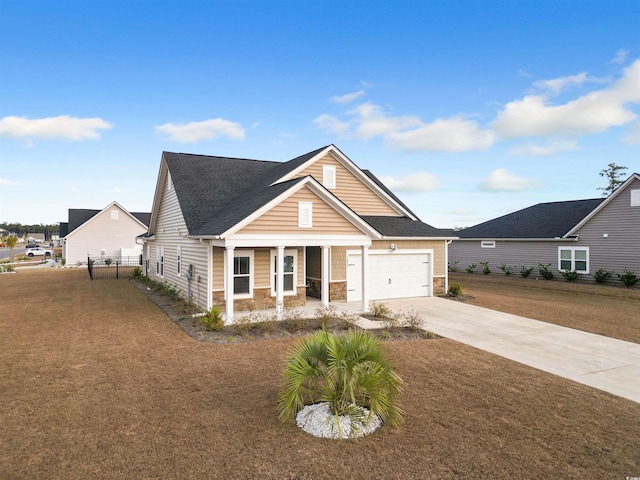 view of front of property featuring a front lawn, driveway, stone siding, a porch, and a garage