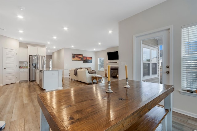 dining room featuring visible vents, baseboards, recessed lighting, light wood-style flooring, and a glass covered fireplace