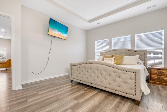 bedroom with wood finished floors, visible vents, and baseboards