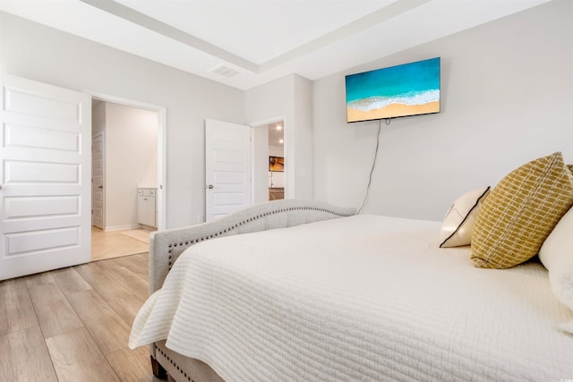 bedroom featuring ensuite bath, visible vents, and light wood finished floors