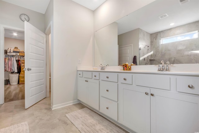 full bathroom with visible vents, double vanity, a sink, a spacious closet, and a walk in shower