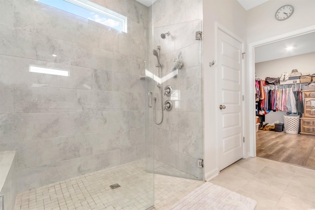 bathroom featuring a spacious closet, tile patterned flooring, and a shower stall