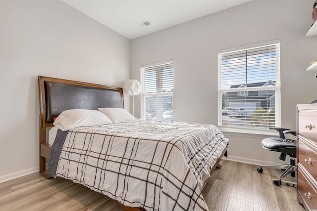 bedroom with multiple windows, wood finished floors, visible vents, and baseboards