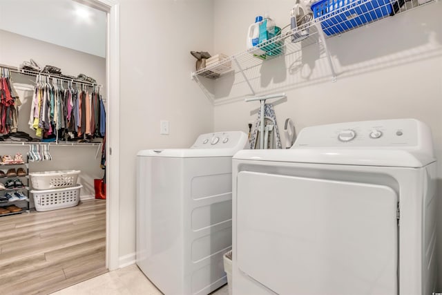 washroom featuring washer and dryer, wood finished floors, and laundry area