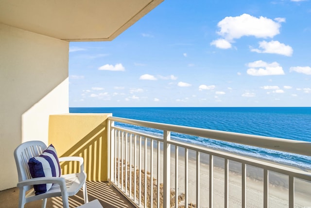 balcony with a water view and a view of the beach