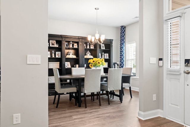 dining room with hardwood / wood-style floors and an inviting chandelier