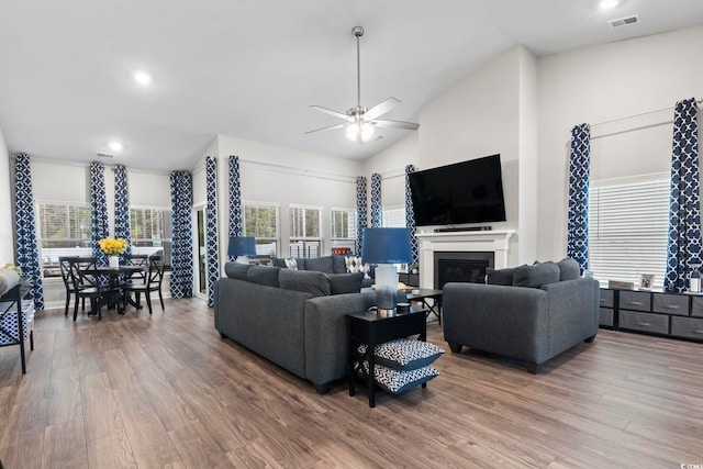 living room with ceiling fan, hardwood / wood-style floors, and vaulted ceiling