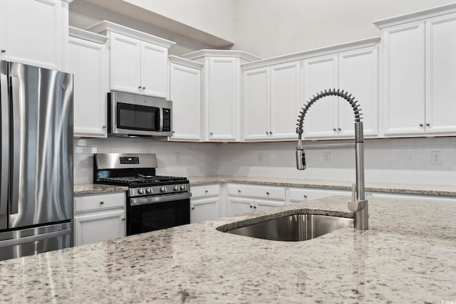 kitchen with stainless steel appliances, white cabinetry, and sink