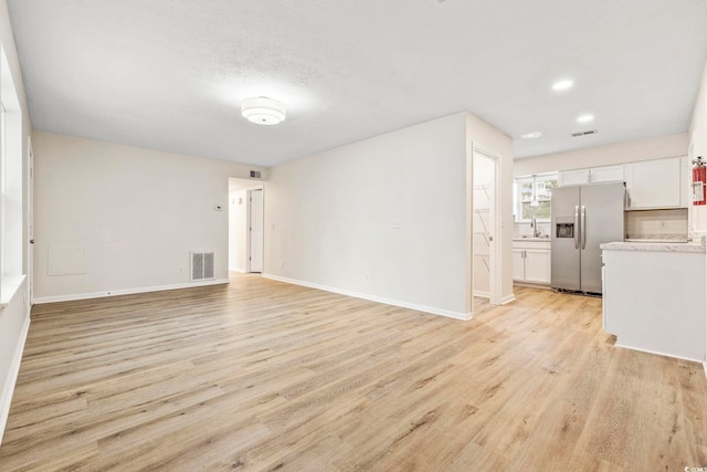 unfurnished living room featuring sink and light hardwood / wood-style flooring