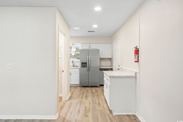 kitchen featuring sink, light hardwood / wood-style flooring, backsplash, stainless steel appliances, and white cabinets