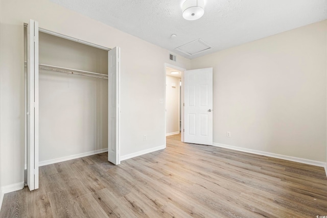 unfurnished bedroom with a textured ceiling, light hardwood / wood-style floors, and a closet