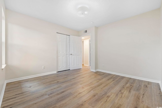 unfurnished bedroom with light wood-type flooring and a closet