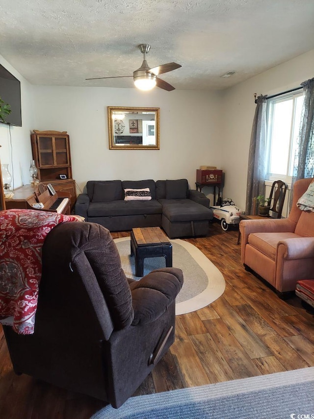 living room with ceiling fan, a textured ceiling, and dark hardwood / wood-style flooring