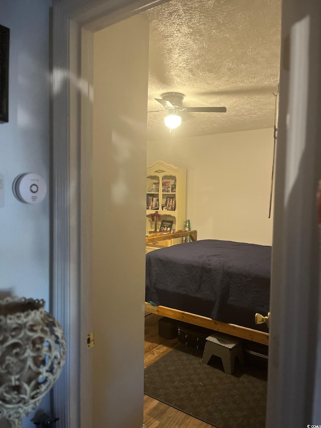 bedroom featuring wood-type flooring, ceiling fan, and a textured ceiling