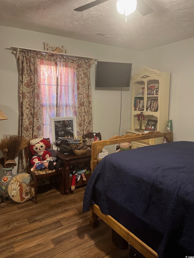 bedroom featuring hardwood / wood-style flooring, ceiling fan, and a textured ceiling