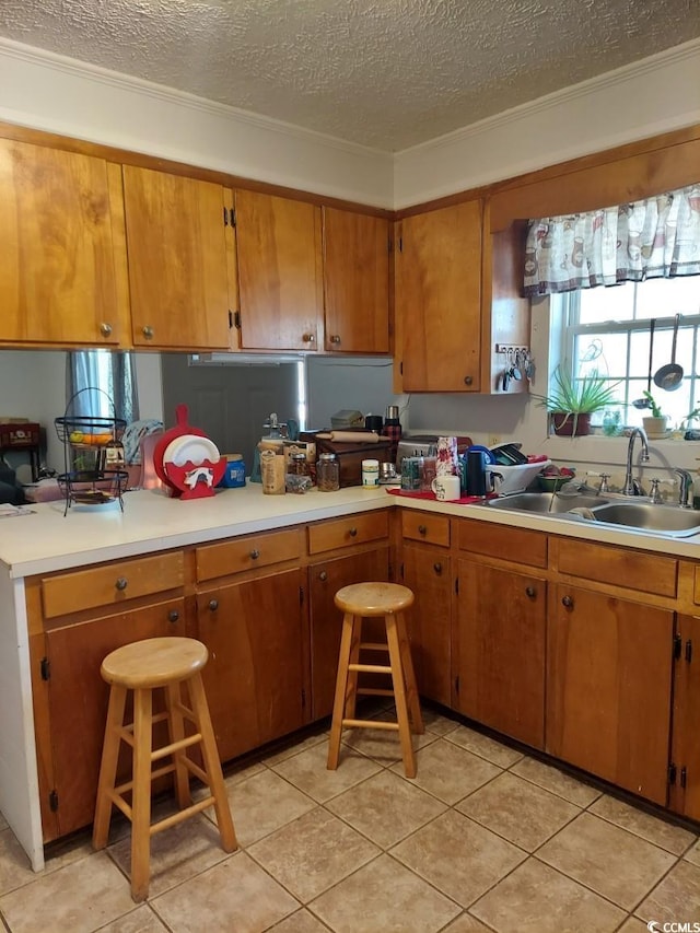 kitchen featuring a kitchen breakfast bar, sink, a textured ceiling, and light tile patterned floors