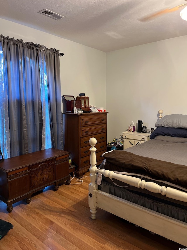 bedroom with ceiling fan, light hardwood / wood-style flooring, and a textured ceiling