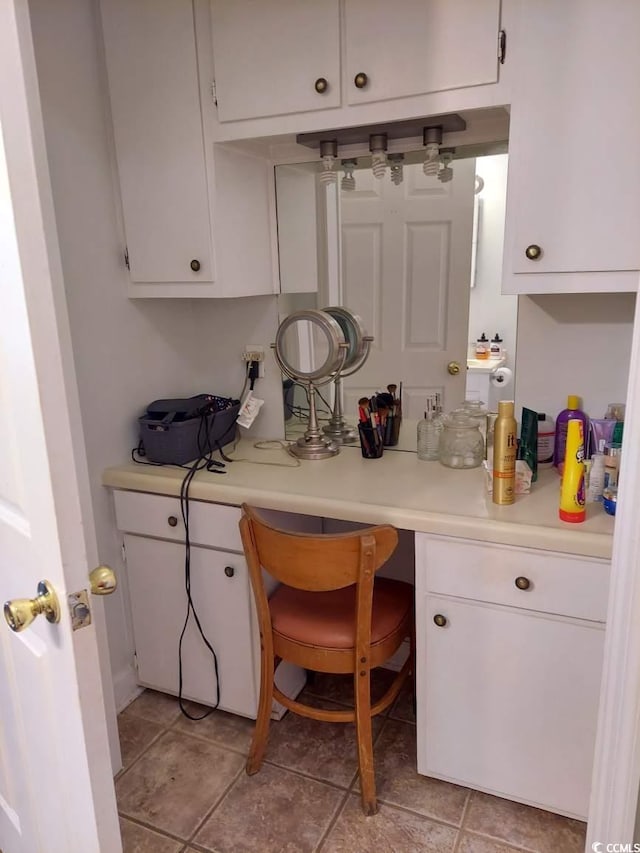 kitchen featuring white cabinetry, built in desk, and light tile patterned flooring