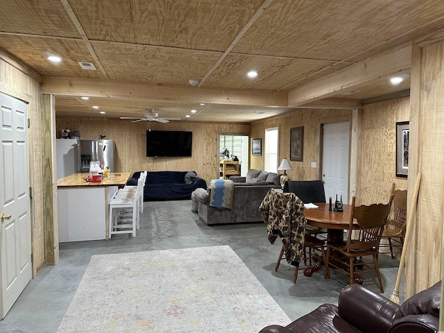 dining room featuring ceiling fan, concrete flooring, wooden ceiling, and wood walls