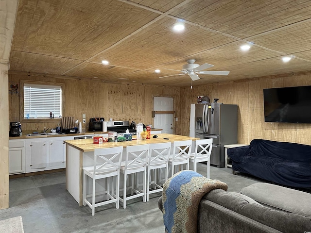 kitchen with butcher block countertops, a breakfast bar area, white cabinetry, stainless steel fridge with ice dispenser, and a kitchen island