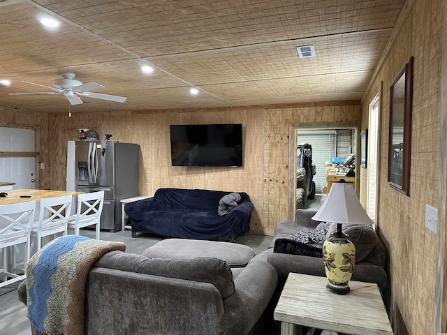 living room featuring ceiling fan and wood walls