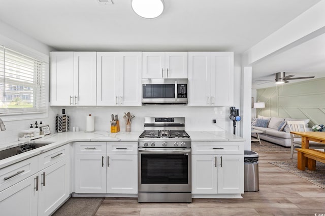 kitchen featuring sink, white cabinets, tasteful backsplash, light hardwood / wood-style flooring, and appliances with stainless steel finishes