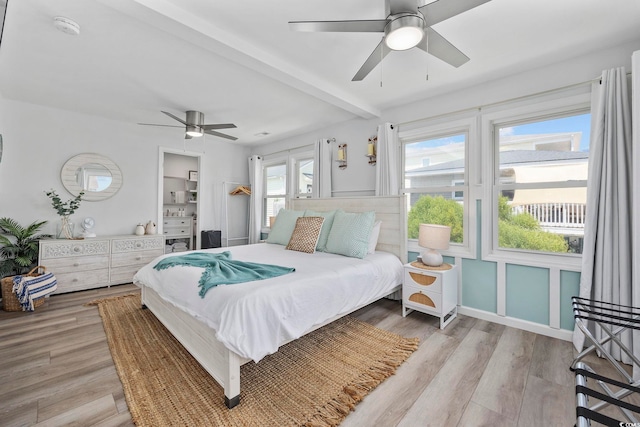 bedroom with beamed ceiling, ceiling fan, and light wood-type flooring