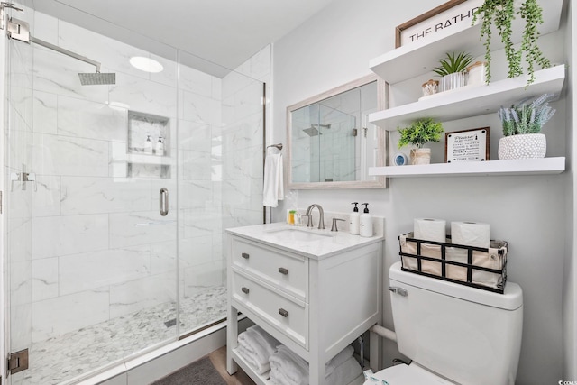 bathroom with a shower with door, vanity, and toilet