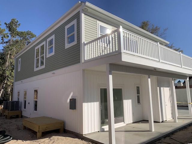 rear view of property featuring cooling unit, a patio area, and a balcony