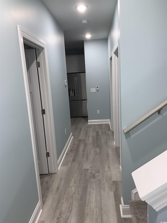 hallway featuring light wood-type flooring and baseboards