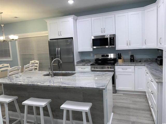 kitchen featuring white cabinets, a kitchen bar, appliances with stainless steel finishes, and a sink