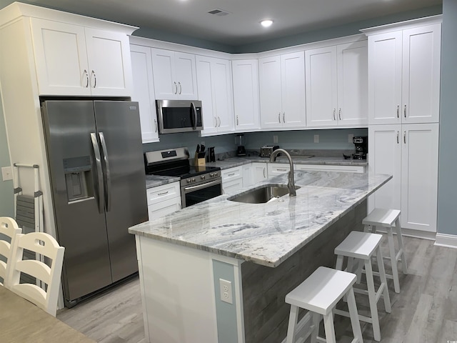 kitchen with light wood-style flooring, a sink, visible vents, white cabinetry, and appliances with stainless steel finishes