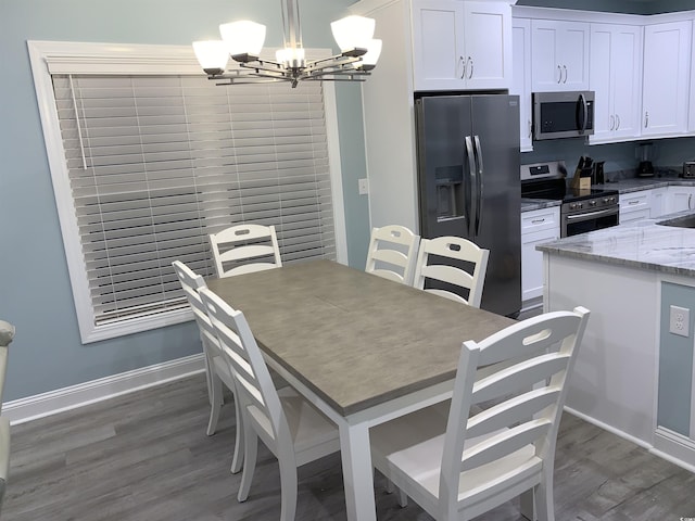 dining space with dark wood-type flooring, baseboards, and a chandelier