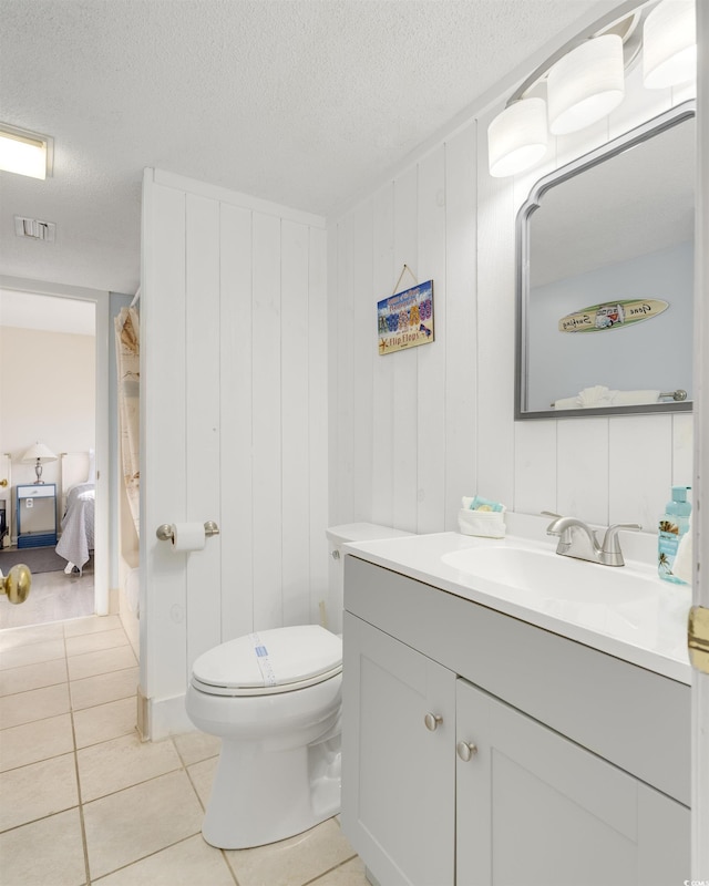 bathroom featuring tile patterned flooring, vanity, a textured ceiling, and toilet