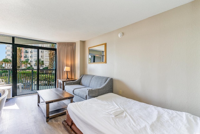 bedroom with floor to ceiling windows, wood-type flooring, and access to exterior