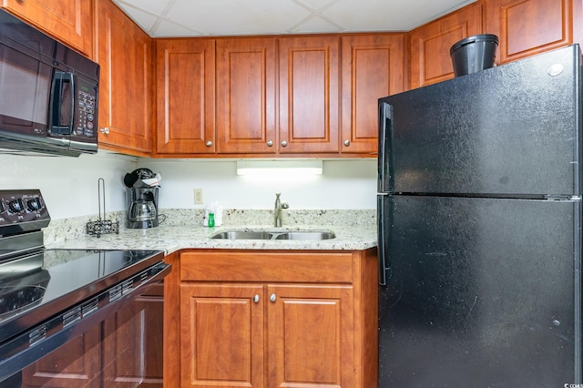 kitchen with sink, light stone counters, a paneled ceiling, and black appliances