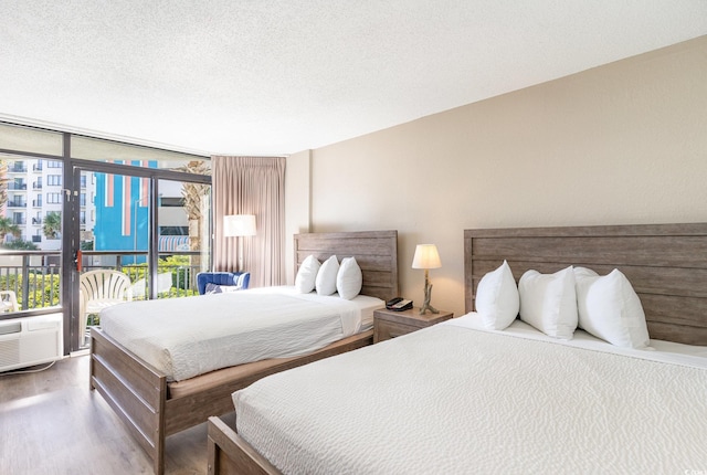 bedroom with access to exterior, hardwood / wood-style floors, a textured ceiling, and expansive windows